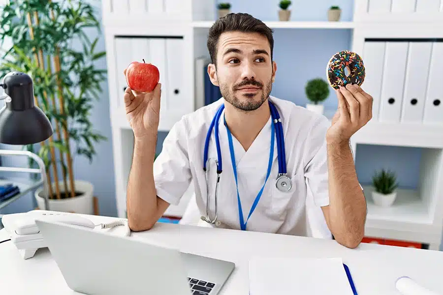 Doctor choosing between apple and donut for heart health.