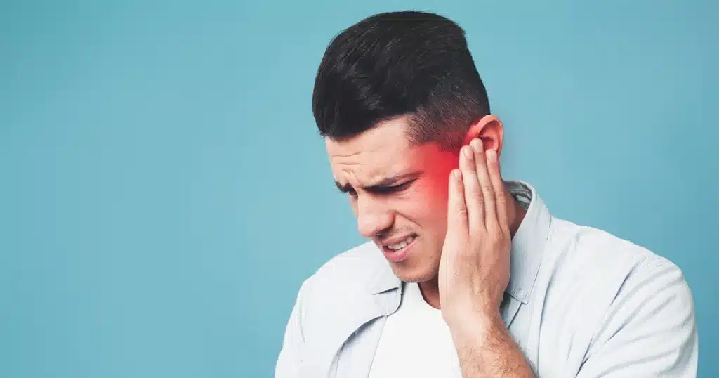 Man holding his ear in pain with a red highlight indicating earache.