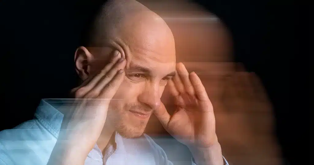 Man holding his head with blurred motion, showing stroke symptoms.