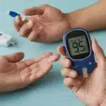 Person using glucometer to check blood sugar level.