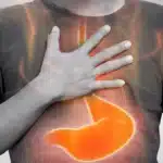 Person holding chest with glowing stomach showing acid reflux pain.