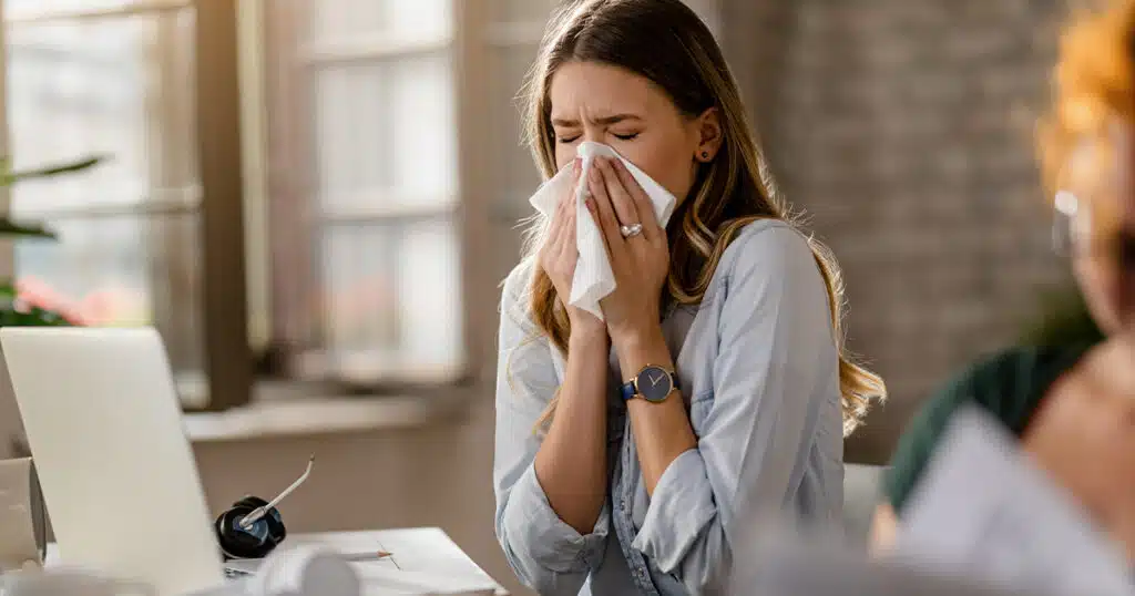 Woman sneezing due to common allergy triggers.