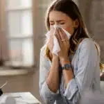 Woman sneezing due to common allergy triggers.