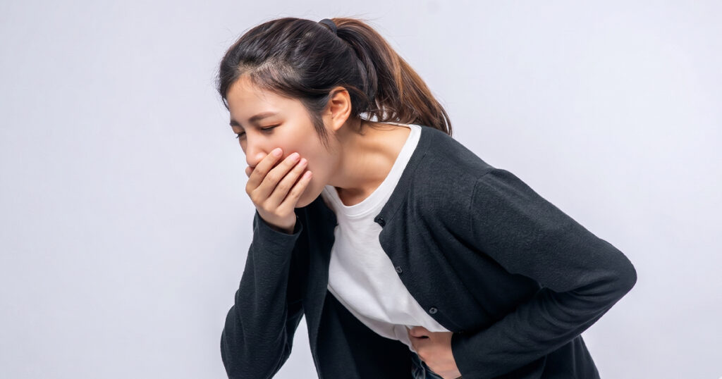 Nauseous woman holding stomach from a UTI.
