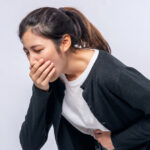 Nauseous woman holding stomach from a UTI.