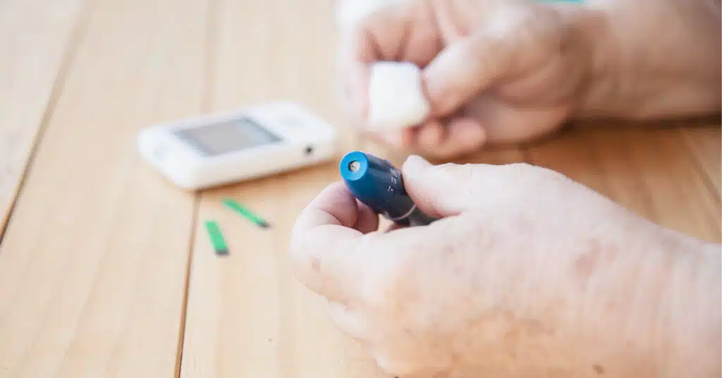 A close-up of a person using a lancing device to perform a blood glucose finger-prick test.