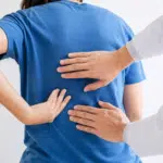 Doctor examining a patient with middle back pain.