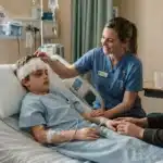 Nurse and mother comforting a hospitalized boy with a head injury.